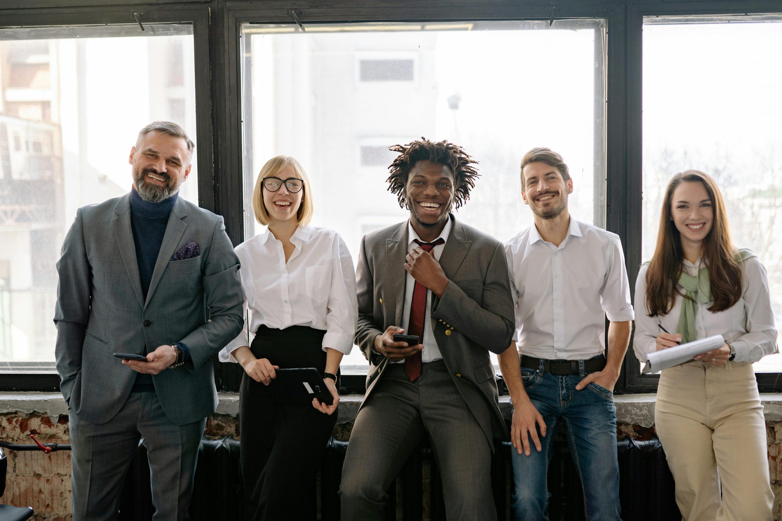 pexels photo 7794035 7794035 A diverse group of business professionals smiling and standing together in the office.